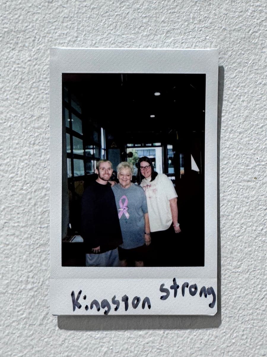 An instant print of three people, displayed on a wall.