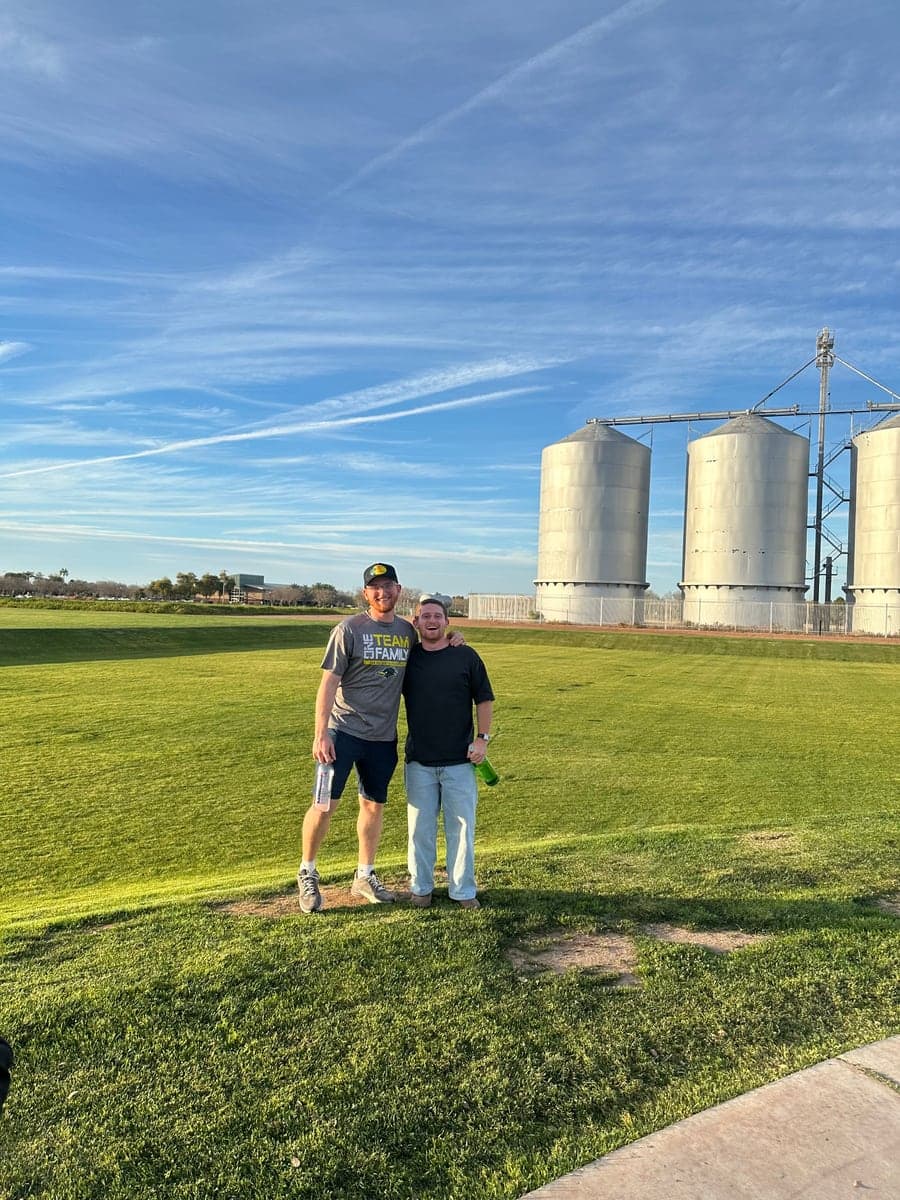 Two people standing on a lawn beside silos.